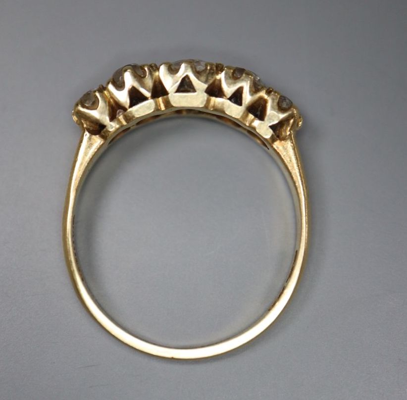 An 18k yellow metal and graduated five stone diamond set half hoop ring, size O, gross 3.8 grams,